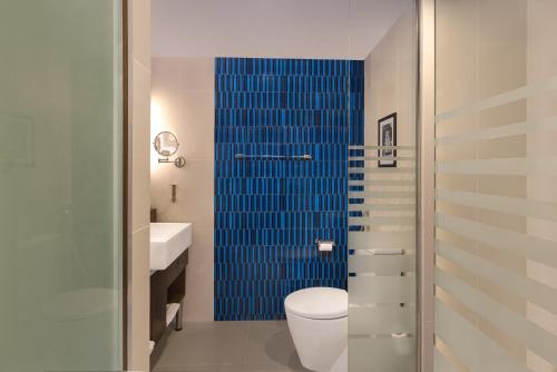 uma casa de banho com um WC e um chuveiro de azulejos azuis em Radisson Hotel Kandy em Kandy