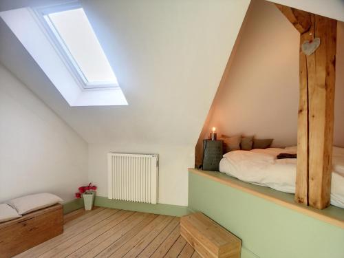 - une chambre mansardée avec un lit et une lucarne dans l'établissement Ô Petit Château, à La-Roche-en-Ardenne