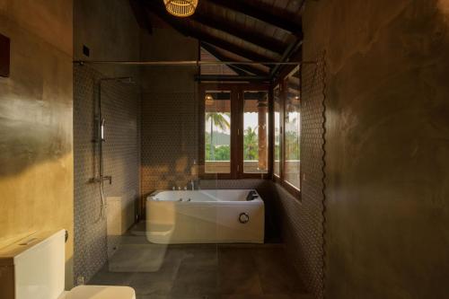 a bathroom with a bath tub and a window at Kiss Blossom in Mirissa