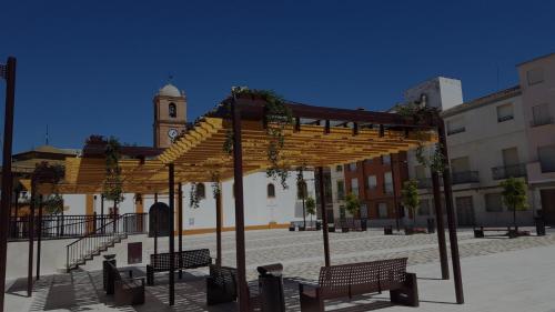 a group of benches in a courtyard with a clock tower at APARTAMENTO ANCHA CENTRO in Huétor-Tájar