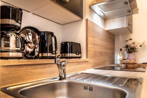 uma cozinha com um lavatório e electrodomésticos em aço inoxidável em komfortable Ferienwohnung in Halle-Kröllwitz 2 em Kröllwitz