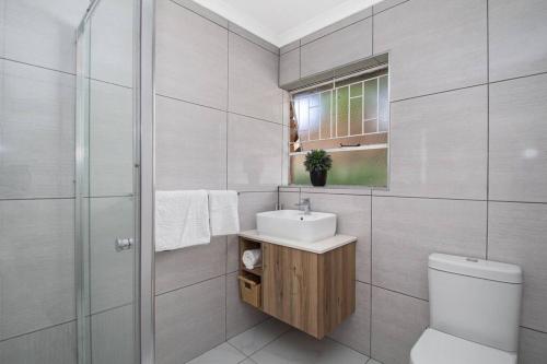a bathroom with a toilet and a sink and a shower at The Cycad. 4-Bed Home next to Clearwater Mall in Roodepoort