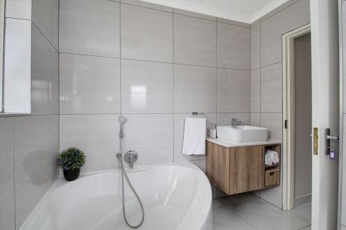 Baño blanco con bañera y lavamanos en The Cycad. 4-Bed Home next to Clearwater Mall en Roodepoort