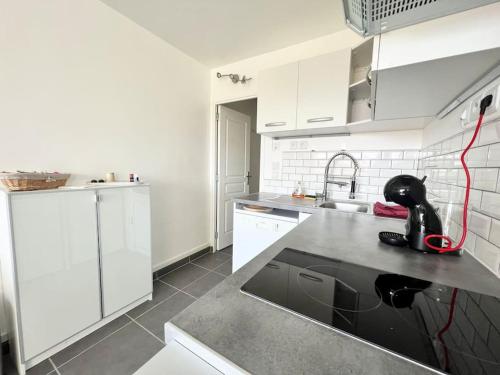 une cuisine avec des armoires blanches et un comptoir noir dans l'établissement Le Peymian 900 m de la plage, à La Ciotat