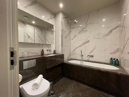 a bathroom with a tub and a toilet and a sink at Stunning 2BA, 2BR Apt, Desirable Chigwell CHCL F6 in Chigwell