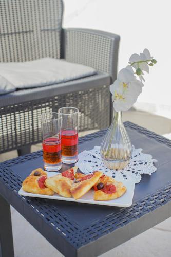 a table with a plate of food and two glasses of juice at Io, te e il mare in Polignano a Mare