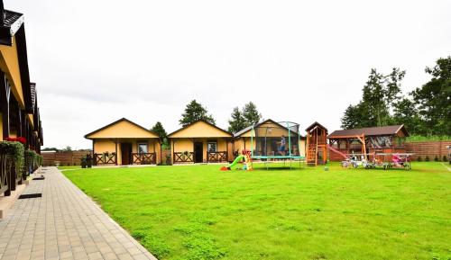 a large yard with a playground with houses at DOMKI NA TURYSTYCZNEJ in Dąbki