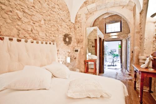 a bedroom with a white bed and a stone wall at B&B Il Marchese Del Grillo in Sulmona