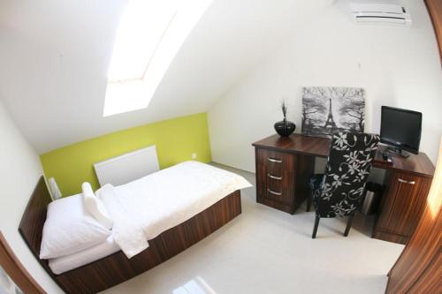 a bedroom with a bed and a desk and a television at Grand hotel/pension in Sládkovičovo
