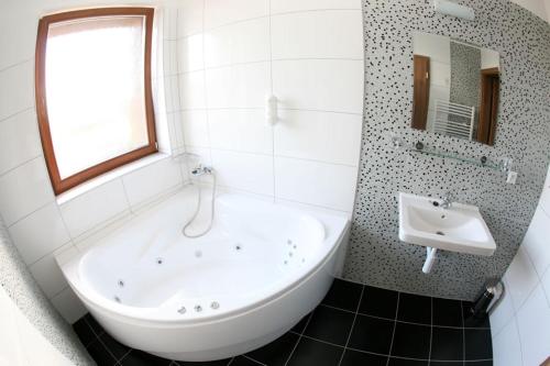 biała łazienka z wanną i umywalką w obiekcie Grand hotel/pension w mieście Sládkovičovo