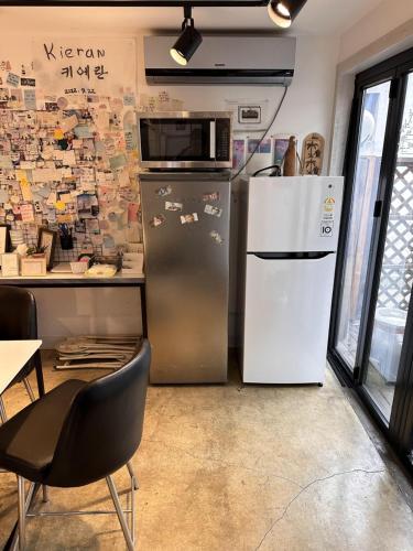 eine Küche mit einem Kühlschrank und einer Mikrowelle an der Wand in der Unterkunft Haru The Guesthouse in Andong