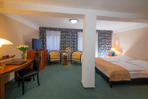a hotel room with a bed and a desk and chairs at Belvedere Spa & Kurhotel in Františkovy Lázně