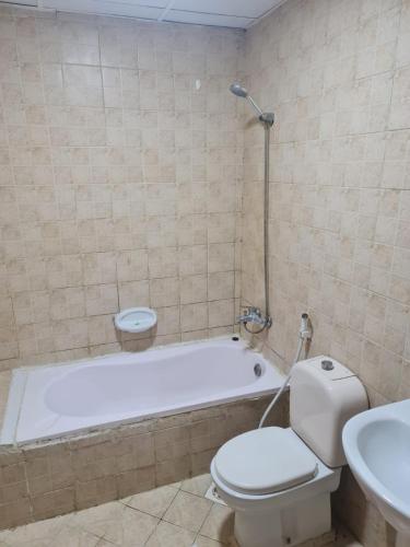 a bathroom with a tub and a toilet and a sink at Almond Tower A5 in Ajman 