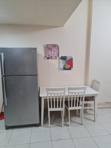 a kitchen with a table and a refrigerator and chairs at Almond Tower A5 in Ajman 