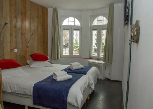 two beds in a room with two windows at Hotel Aan Zee in De Panne