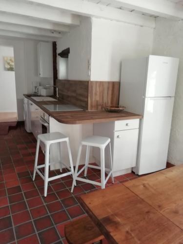 - une cuisine avec un réfrigérateur blanc et deux tabourets dans l'établissement Gîte de caractère, à Thauron