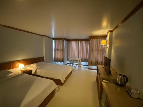 Cette chambre comprend 2 lits et une table. dans l'établissement Naraigrand Hotel (โรงแรมนารายณ์แกรนด์), à Chai Badan