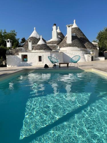 a swimming pool with a chair and a house at Trullo Matilde in Martina Franca