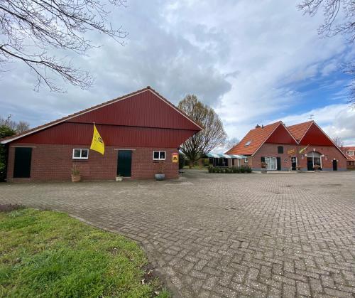 un gran edificio rojo con un letrero amarillo. en De Schuure 't Voorde in Winterswijk, en Winterswijk