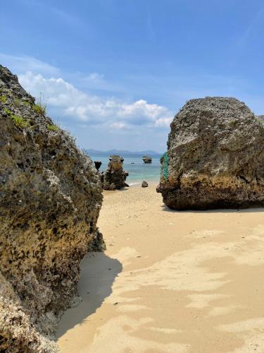 a sandy beach with large rocks and the ocean at Premium Villa Miyagi Island in Ikei