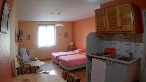 a small room with a bed and a kitchen at Résidence L'Alexandra 2 étoiles in Bourbonne-les-Bains