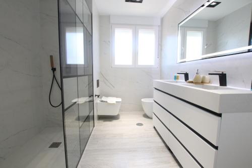 bagno bianco con lavandino e specchio di TESS Villa Paz ad Alhaurín de la Torre