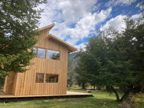 On aperçoit une maison en bois entourée d'arbres. dans l'établissement Preciosa casa V. Cerro Castillo cercana Parque, à Villa Cerro Castillo