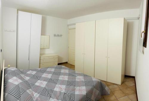 a bedroom with white cabinets and a bed with a checkered blanket at Appartamento centro storico Conegliano in Conegliano