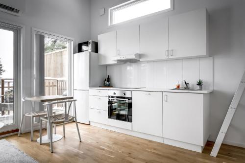 a kitchen with white cabinets and a table and a stool at Relaxing Lake Oasis with Jacuzzi - Amazing view & Private Pier in Stockholm