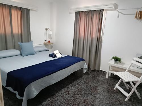a bedroom with a bed and a chair and a window at Pensión Playa in Los Cristianos