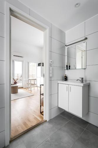 a white kitchen with a sink and a mirror at Relaxing Lake Oasis with Jacuzzi - Amazing view & Private Pier in Stockholm
