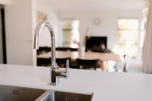 a kitchen sink with a kitchen in the background at Nelson Central Town House in Nelson