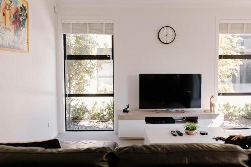 a living room with a couch and a tv and windows at Nelson Central Town House in Nelson