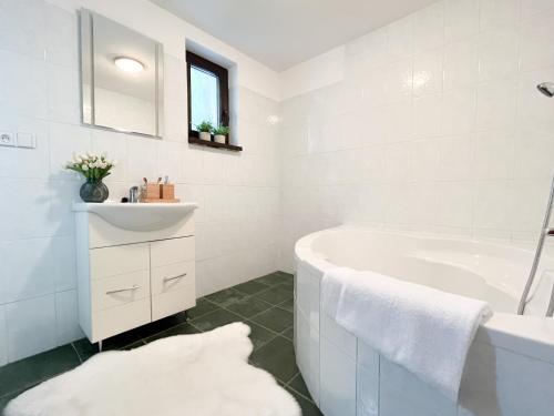 ein weißes Badezimmer mit einer Badewanne und einem Waschbecken in der Unterkunft Chata POHODA Nitrianske Rudno in Nitrianske Rudno