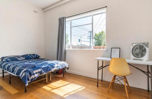 a bedroom with a bed and a desk and a window at Richmond Private Rooms - 151 Hoddle Homestay in Melbourne