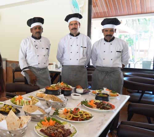 three chefs standing in front of a table of food at Aananda Wellness and Resorts in Dharmastala