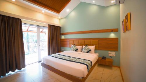 Dharmastala的住宿－Aananda Wellness and Resorts，一间卧室设有一张床和一个大窗户