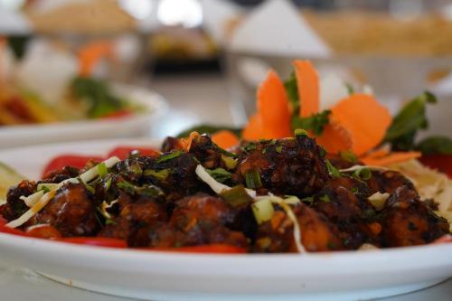 a plate of food with meat and vegetables on a table at Aananda Wellness and Resorts in Dharmastala