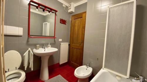 bagno con lavandino, servizi igienici e specchio di Residence I LAMPONI incantevole trilocale casa vacanze 6 posti letto a Dimaro