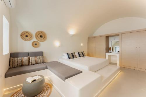 a white bedroom with a bed and a couch at Cilon Suites Santorini in Imerovigli