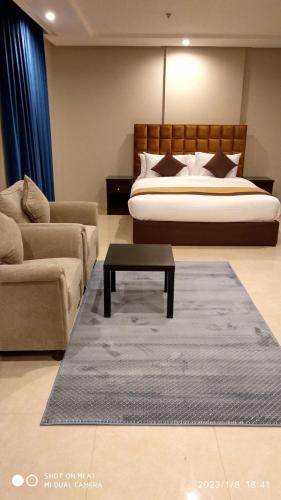 a bedroom with a bed and a couch and a table at يان للشقق المخدومة - Yan Apartments in Jeddah