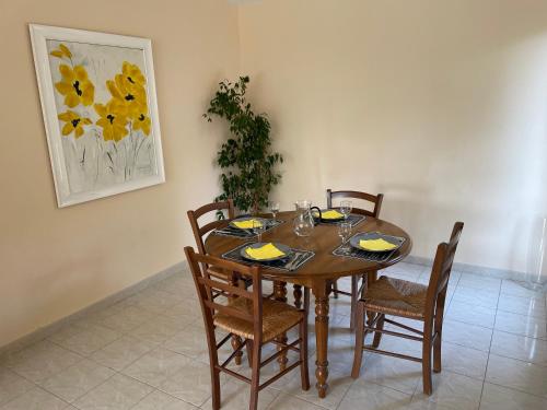 a dining room table with chairs and a painting of yellow flowers at Verdi 1 in Aix-en-Provence