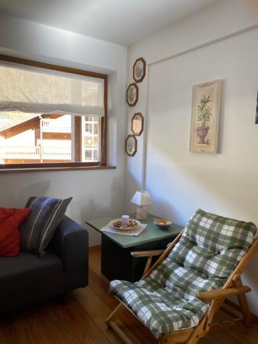 a living room with a couch and a table and a chair at Residence I LAMPONI incantevole trilocale casa vacanze 6 posti letto in Dimaro