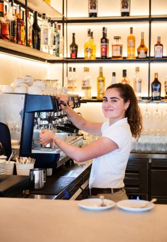 a woman is making a drink at a bar at Hotel Cala Fornells in Paguera