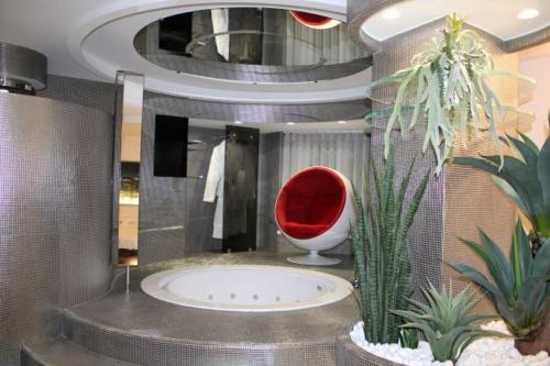 baño con silla roja y algunas plantas en DOMUS Grand Hotel, en Rende