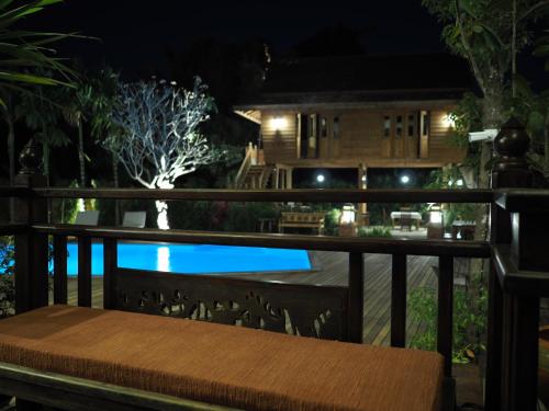 a wooden bench sitting on a balcony at night at Amata Lanna Village อมตะล้านนาวิลเลจ in Chiang Mai