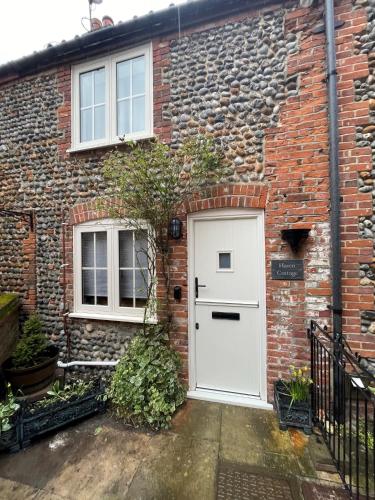 a white front door of a brick house at Haven Cottage, Cromer in Cromer