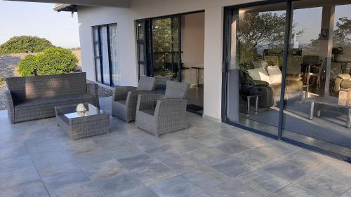 a patio with wicker chairs and a table and windows at Oribi Gorge Villa in Glendale