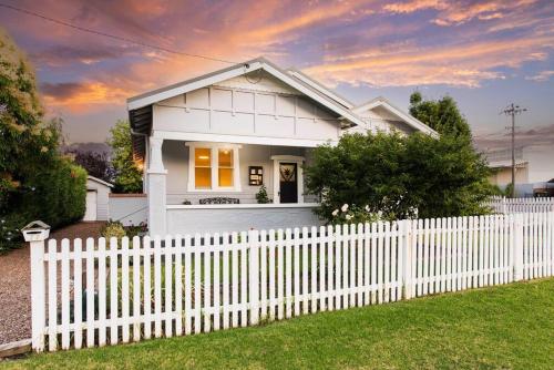 a white house behind a white picket fence at The Birdhouse - Your Well-deserved Country Retreat in Mudgee