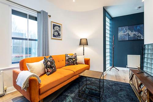 an orange couch in a living room with a window at Gorgeous Roehampton Flat in London